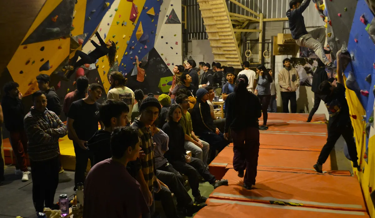 El galpón lleno durante el aniversario: gente sentada en las colchonetas mientras alguien escala a la derecha