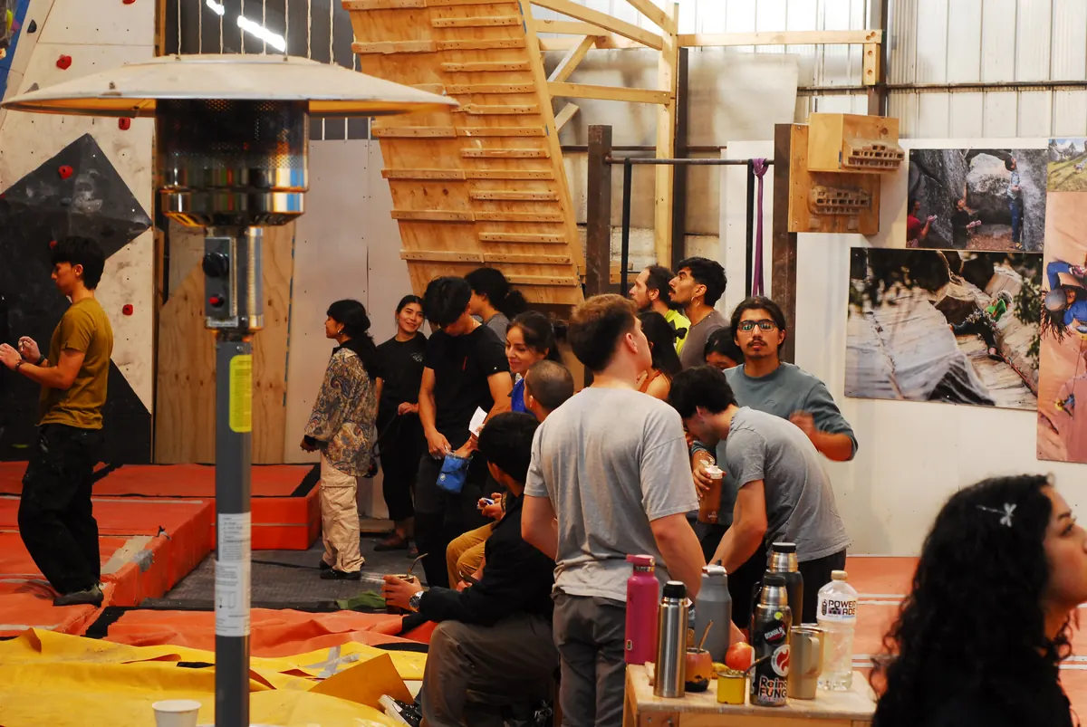 Público reunido junto a la estufa durante una competencia, con el muro y la escalera de madera al fondo