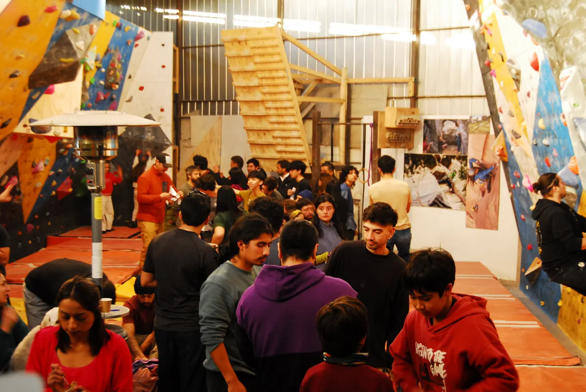 Mucha gente reunida dentro del gimnasio durante un evento, con los muros al fondo