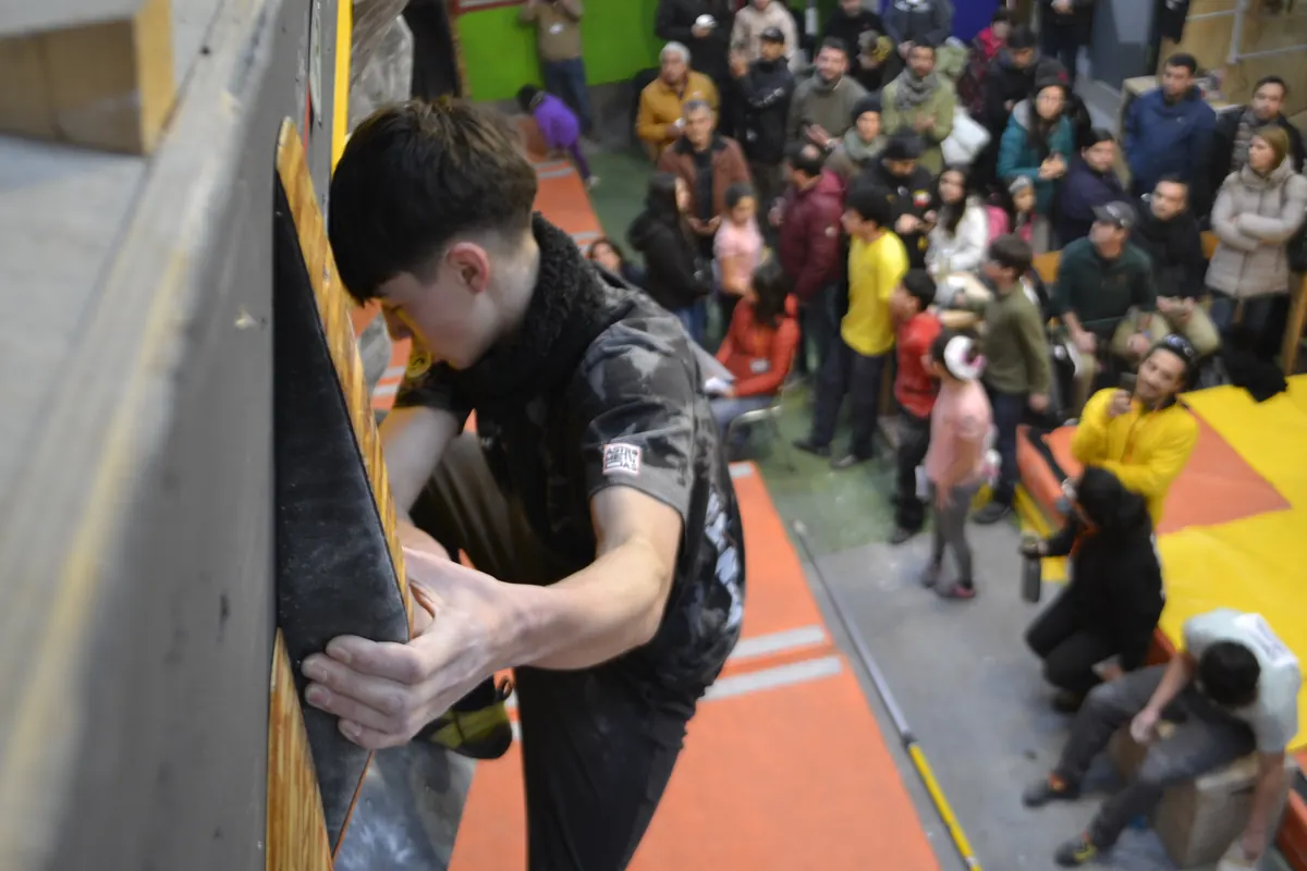 Joven escalando visto desde arriba, con público alrededor