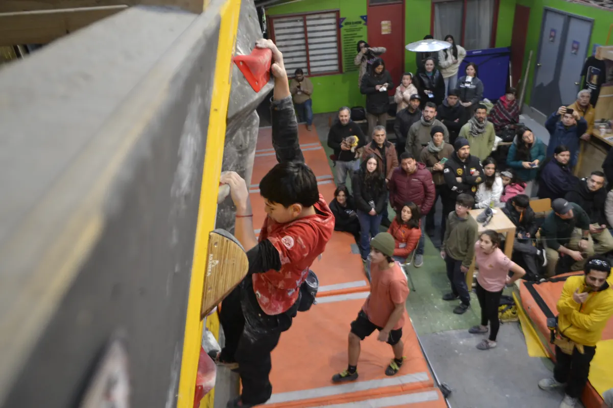 Niño escalando mientras el público lo mira desde abajo