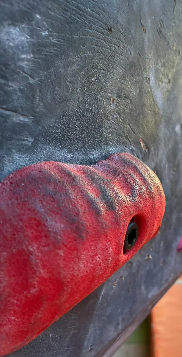 Una presa roja grande atornillada a un volumen negro, vista de muy cerca